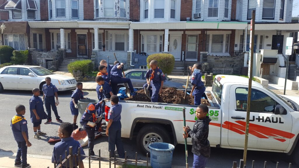 Crowd gathered around a pickup truck with people holding signs and banners.