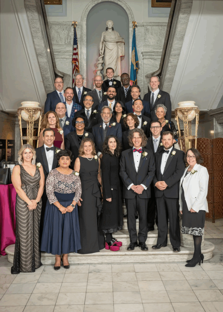 Group photo of formally dressed people on a grand staircase.