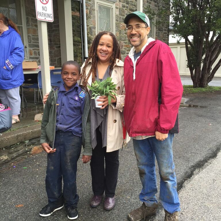 A happy family standing on a sidewalk, smiling at the camera.