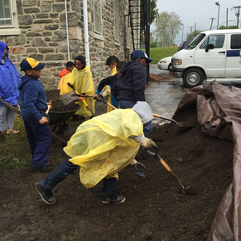 People working together to spread soil or compost outdoors.
