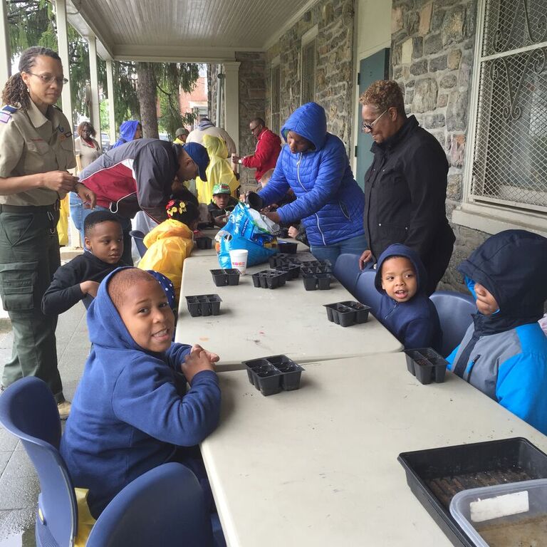 Children engaged in a hands-on activity at a long table, supervised by adults.