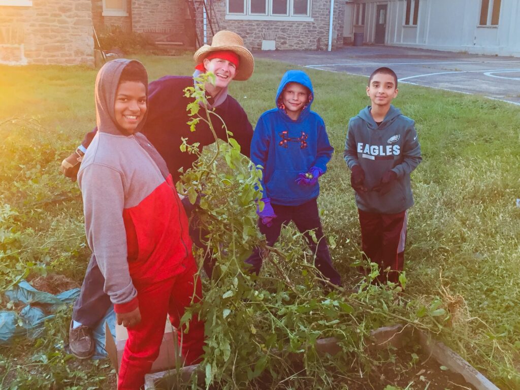 Three people smiling together in a lush garden at sunset.