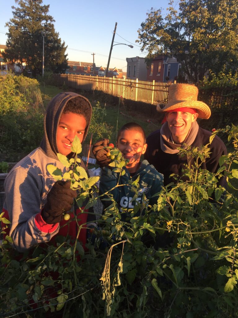 Three people smiling together in a lush garden at sunset.