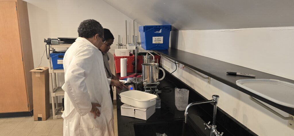 Scientists in lab coats working with lab equipment at a countertop.