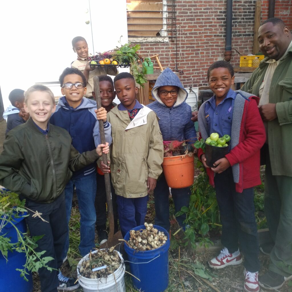 Group of children and an adult gardening together outdoors.