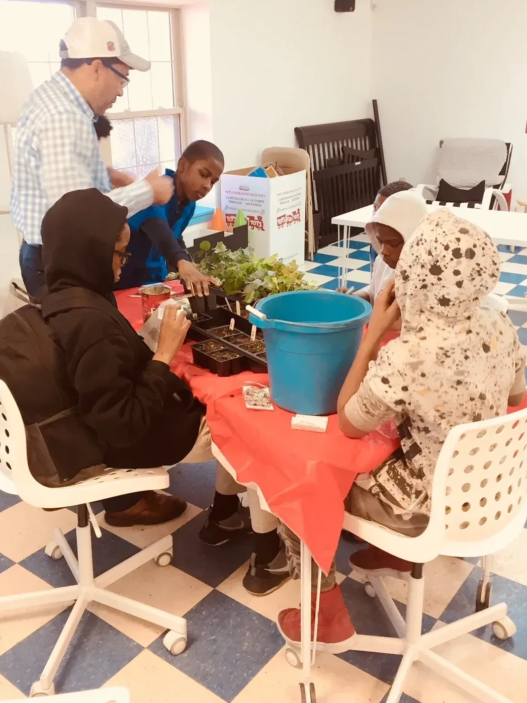 A group of people gathered around a table preparing plants indoors.